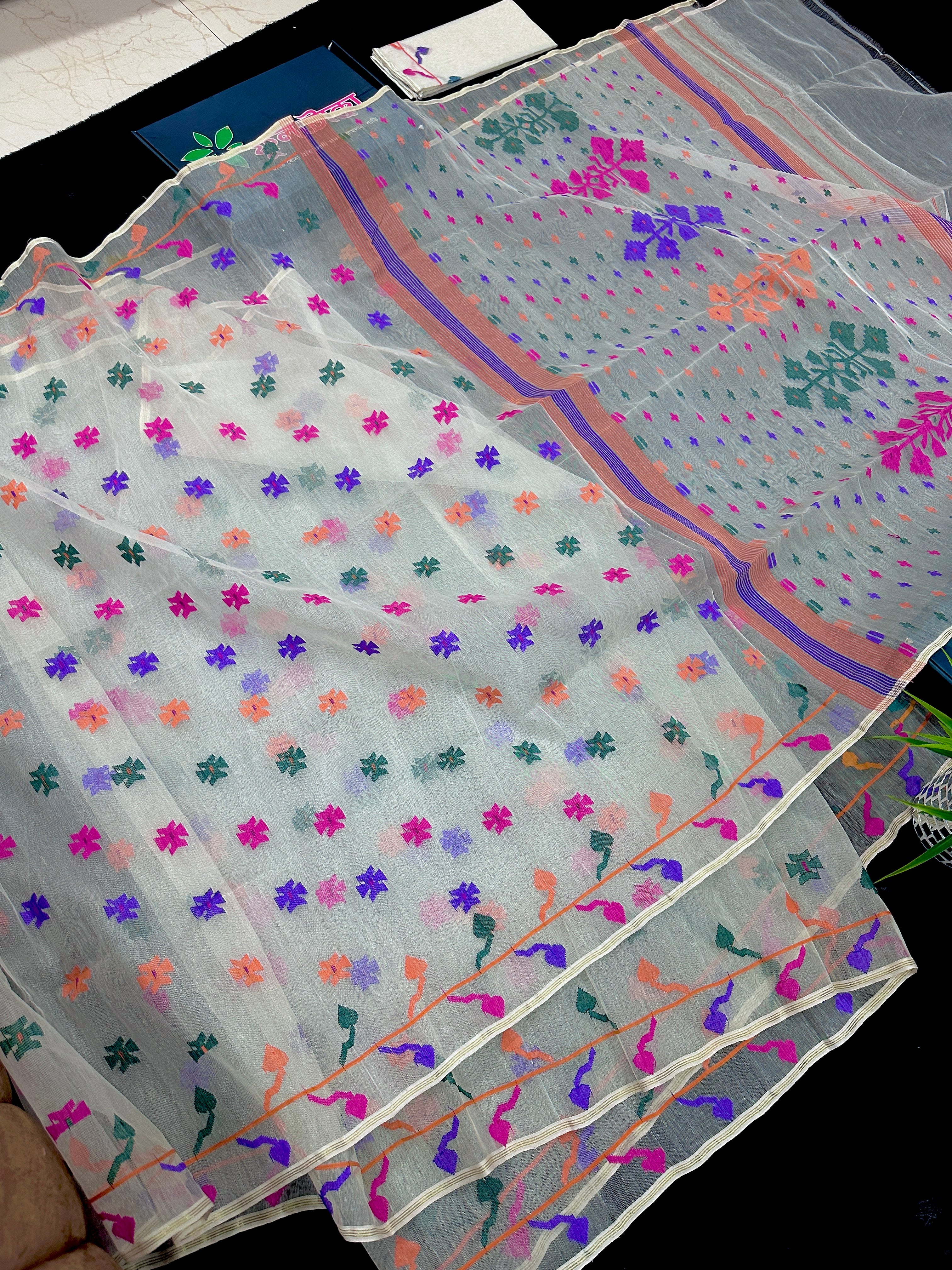 White jamdani saree with purple pink green orange threads work.