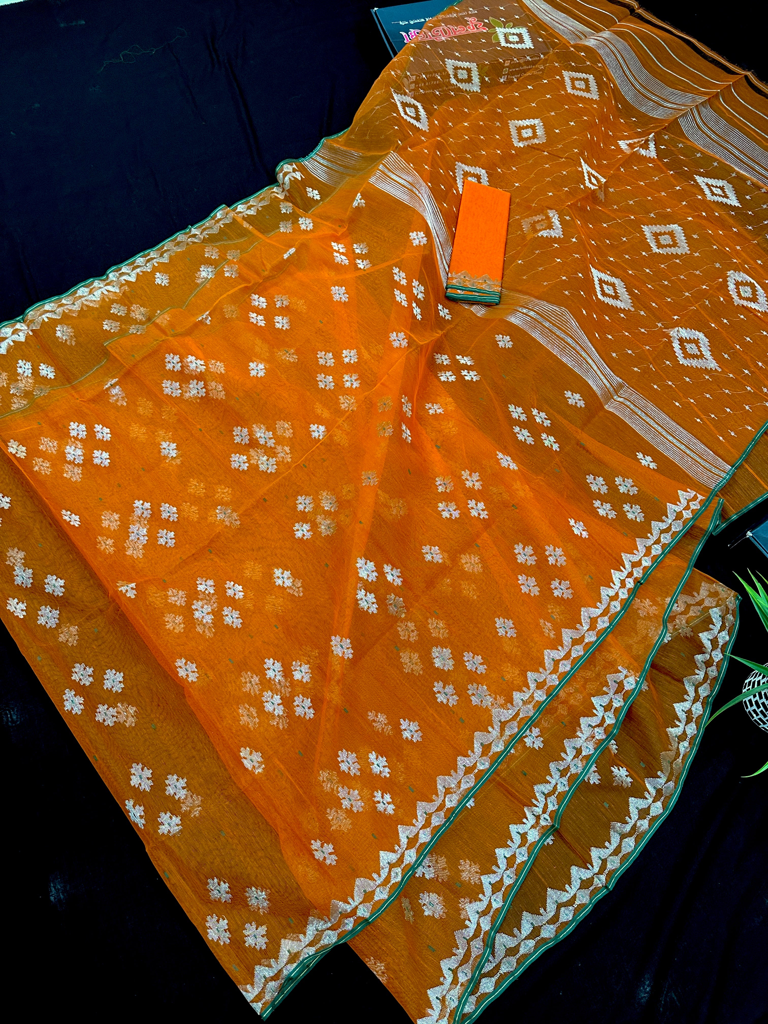 Orange soft jamdani saree with silver jori work & green border.