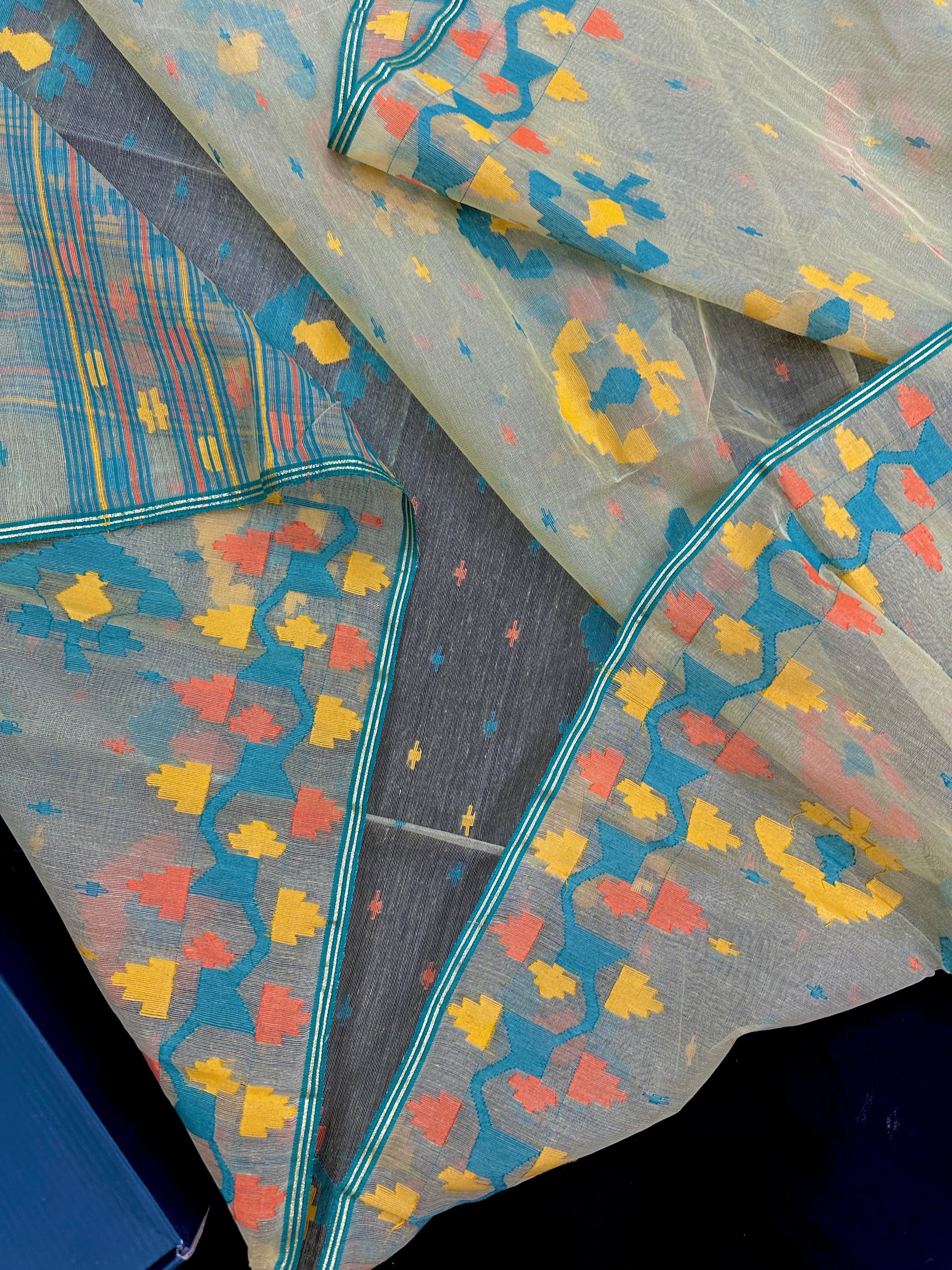 Cream colour jamdani saree with yellow orange blue floral threads work and blouse piece.