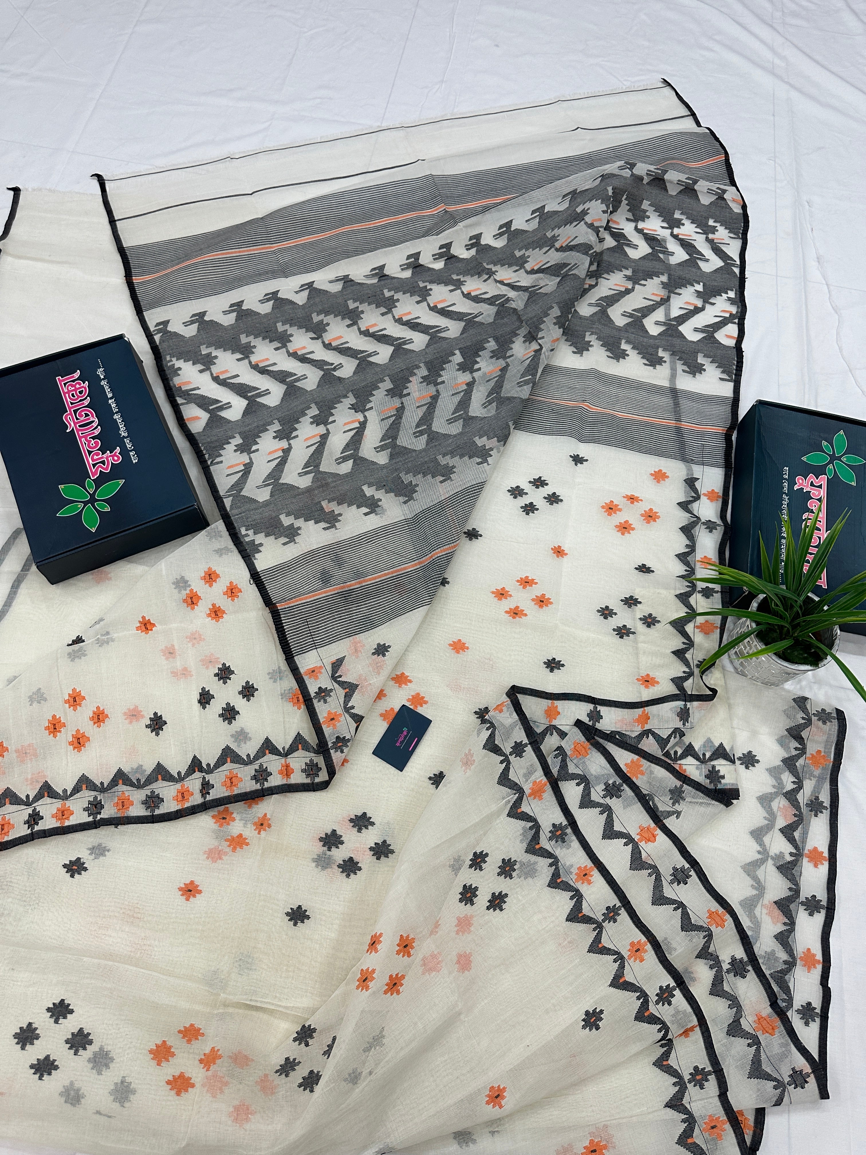 White cotton jamdani saree with orange & black threads work.